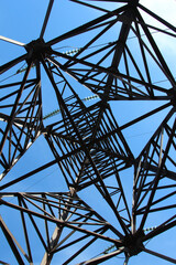 A fragment of the construction of the tower of the high-voltage line against the blue sky. Metalwork concept