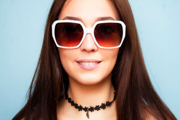 Closeup woman portrait in sunglasses on a blue background. Brunette wearing sunglasses.