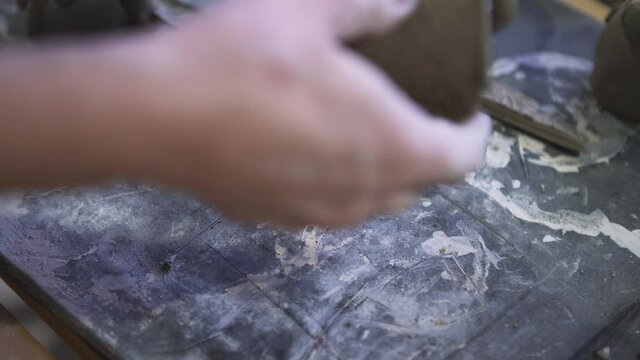 Raw clay with beautiful cut floral ornament. Clip. Close up of male hands making decorative dish from raw clay in a workshop, ceramics works concept.