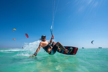 kiter does a difficult trick on a background of transparent water and blue sky