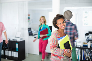 Businesswoman carrying folders in office