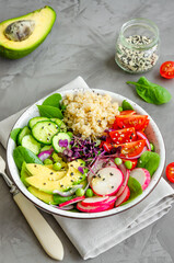 Quinoa salad with fresh vegetables, spinach, green peas, microgreens and sesame seeds in a bowl in a concrete background. Healthy food concept. Vertical orientation.