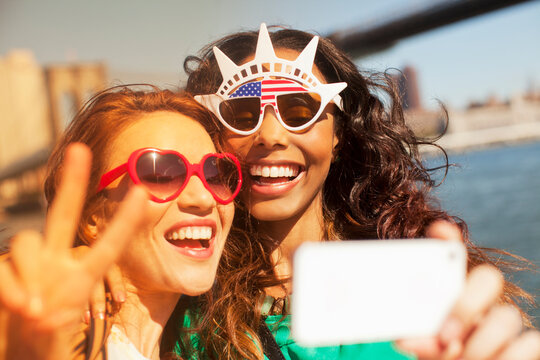 Women taking picture of themselves in novelty sunglasses