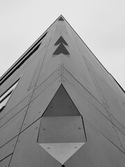 The corner of a concrete panel clad building with chamers and edges creating perspective lines on a monochrome background