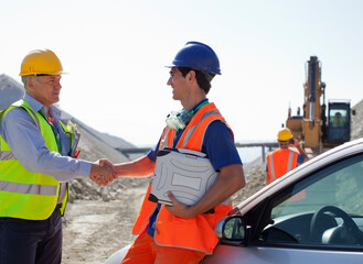 Worker and businessman shaking hands in quarry