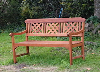 Ornate park bench on the grass in front of some lush woodland