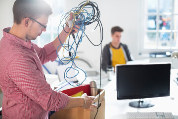 Businessman untangling cords in office