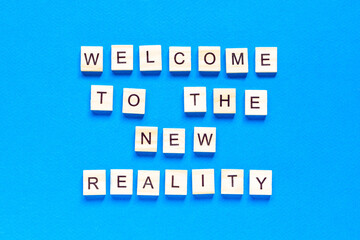 the inscription welcome to the new reality in wooden letters on a blue background. Modern technologies, a new device of the world. the view from the top.