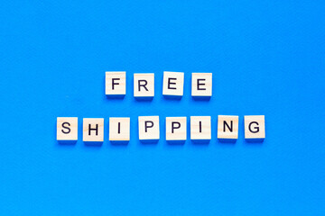 free shipping lettering in wooden letters on a blue background, top view. Service concept, delivery, promotion, free of charge.