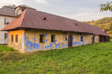 Obraz premium Old Abandoned Residential House Built of Mudbricks, Red Metal Roof a Typical Slovakian Architecture in Past.