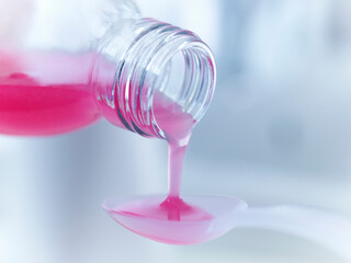 Close up of medicine pouring into measuring spoon