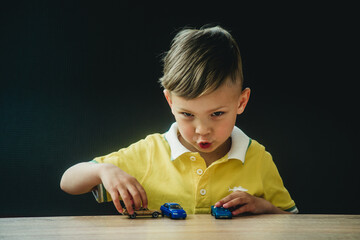 a boy in a bright T-shirt plays in a multi-colored designer at the table