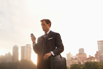 Businessman using cell phone in urban park