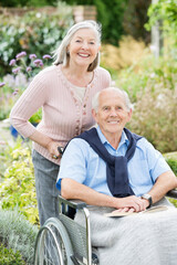 Fototapeta premium Older woman pushing husband's wheelchair outdoors