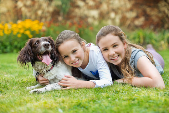 Smiling girls relaxing with dog on lawn