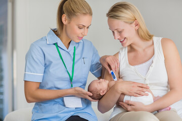 Mother and nurse taking newborn baby's temperature