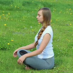 Young woman of European appearance does yoga in summer nature