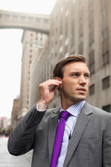 Businessman listening to earphones on city street