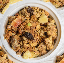 Muesli in a round jar on at abstract  white background with sprinkled crumbs. Diet breakfast with milk or yogurt.