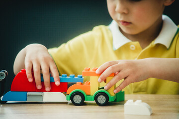 little and happy boy plays in color constructor at the table on gray background