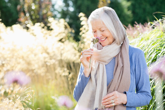 Older woman smelling flowers outdoors