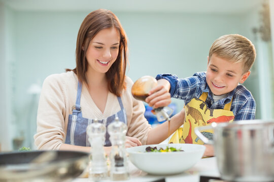 Mother and son making salad in kitchen