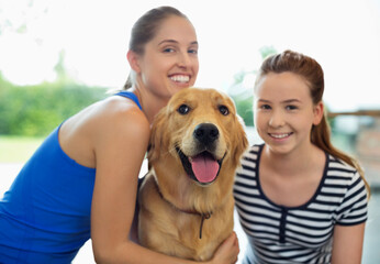 Mother and daughter smiling with dog