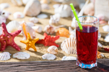 Strawberry juice in a glass on the shore of the sea beach on a sunny day. Sunny rest during the holidays.