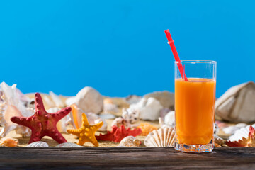 Orange juice in a glass on the shore of the sea beach on a sunny day. Sunny rest during the holidays.