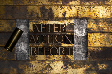 Photo of real authentic typeset letters forming text After Action Report with bullet casing on vintage textured silver grunge copper and gold background