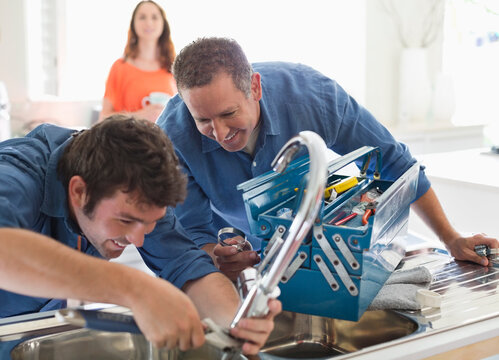 Plumbers Working On Kitchen Sink