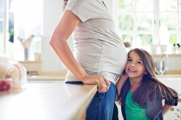 Girl listening to pregnant mothers belly