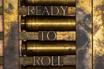 Photo of real authentic typeset letters forming text Ready to Roll on vintage textured silver grunge copper and gold background