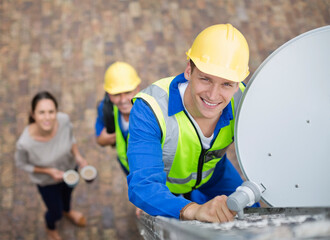 Workers installing satellite dish on roof
