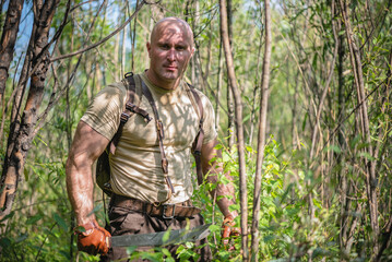 Adventurer man with a machete in the green forest concept.