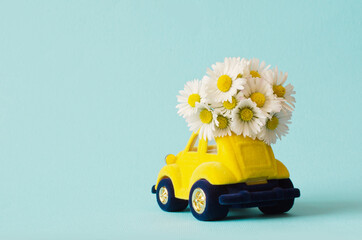 Card with a little toy car delivering bouquet flowers on blue background.