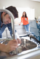 Woman watching plumber work on kitchen sink