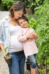 Pregnant mother and daughter gardening together