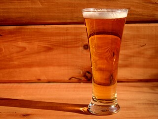 one glass of lager beer on a wooden background