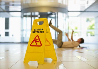 Businessman slipping on wet office floor