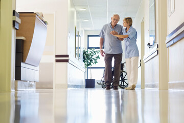 Nurse helping patient walk in hospital hallway