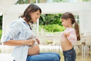 Obraz na płótnie Canvas Girl and pregnant mother comparing bellies