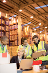Businesswoman and workers talking in warehouse - obrazy, fototapety, plakaty