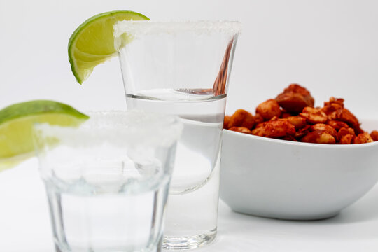 Caballito shot de tequila con cacahuates enchilados fondo blanco