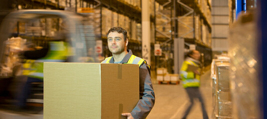 Worker carrying box in warehouse