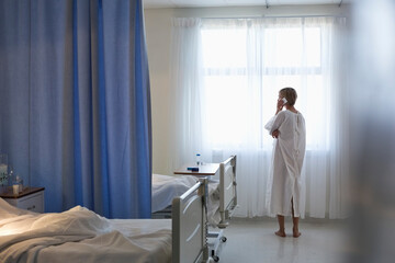 Patient in gown talking on cell phone in hospital room