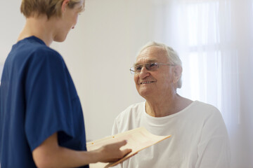 Nurse talking to older patient in hospital room