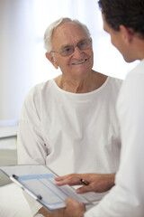 Fototapeta na wymiar Doctor talking with older patient in hospital room