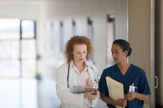 Doctor and nurse talking in hospital hallway