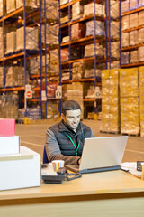 Worker using laptop in warehouse